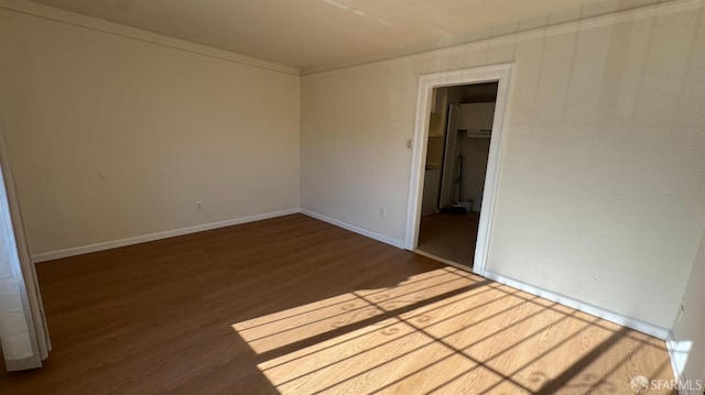 spare room featuring baseboards and wood finished floors