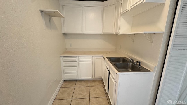 kitchen with light tile patterned floors, open shelves, a sink, light countertops, and white cabinets