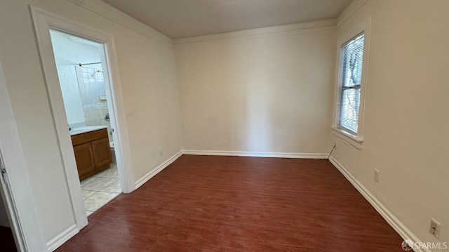 empty room with ornamental molding, baseboards, and wood finished floors