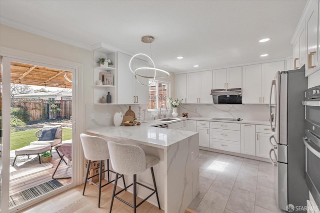 kitchen with light stone counters, a peninsula, a sink, white cabinetry, and tasteful backsplash