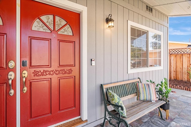 property entrance with covered porch and fence