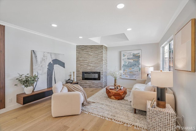 living room with ornamental molding, recessed lighting, a large fireplace, and wood finished floors