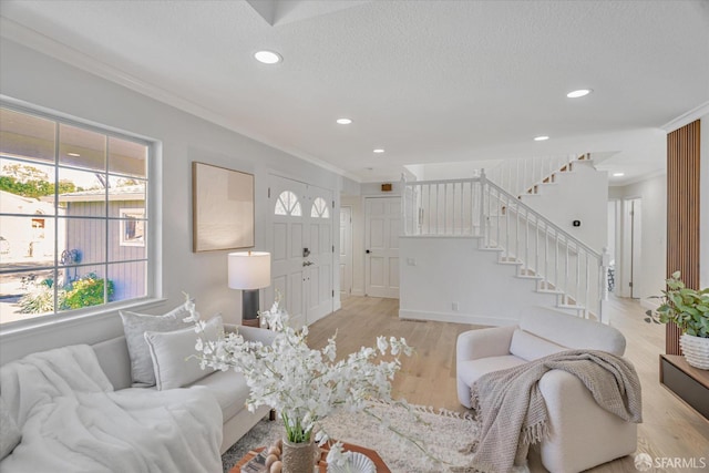 living area with a textured ceiling, recessed lighting, light wood-style floors, stairs, and ornamental molding