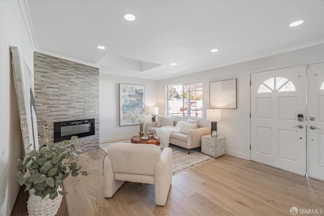 living area featuring baseboards, light wood-style flooring, crown molding, a fireplace, and recessed lighting