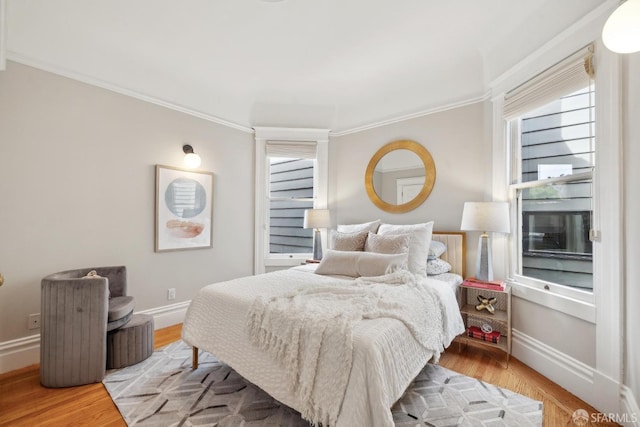 bedroom with ornamental molding, multiple windows, and wood finished floors