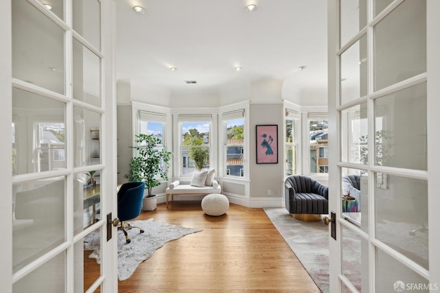 interior space featuring visible vents, a healthy amount of sunlight, french doors, and wood finished floors
