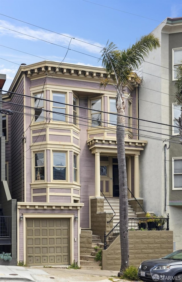 view of front of house with an attached garage, a balcony, and driveway