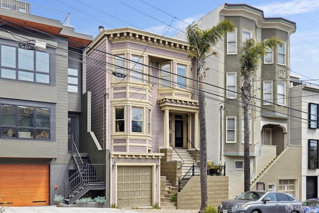 view of front of property featuring an attached garage, stucco siding, and stairway