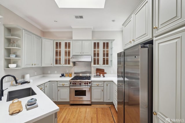 kitchen featuring visible vents, stainless steel appliances, a sink, ornamental molding, and under cabinet range hood