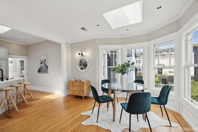 dining area featuring visible vents, light wood finished floors, a healthy amount of sunlight, and a skylight