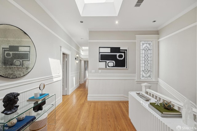 hallway with visible vents, a skylight, wainscoting, light wood finished floors, and recessed lighting