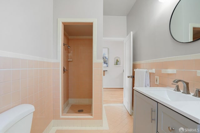 bathroom featuring tile walls, wainscoting, vanity, a shower stall, and tile patterned floors