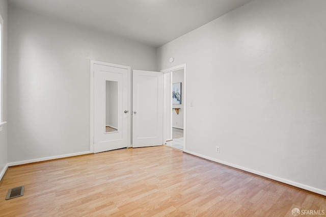 spare room with light wood finished floors, visible vents, and baseboards