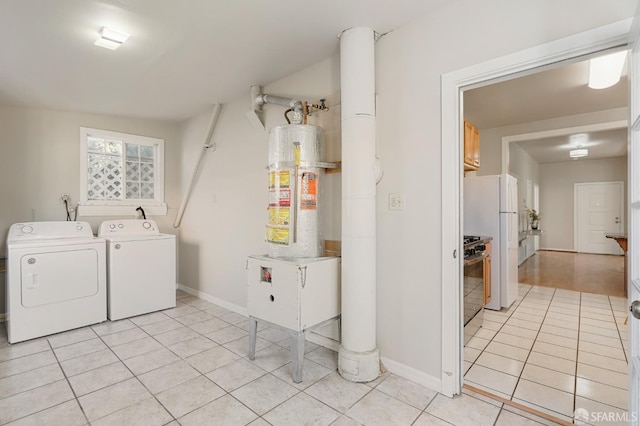 washroom with gas water heater, washer and clothes dryer, light tile patterned floors, laundry area, and baseboards