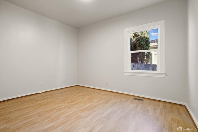 spare room featuring visible vents, baseboards, and wood finished floors