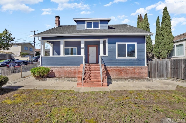 bungalow with roof with shingles, a chimney, and fence