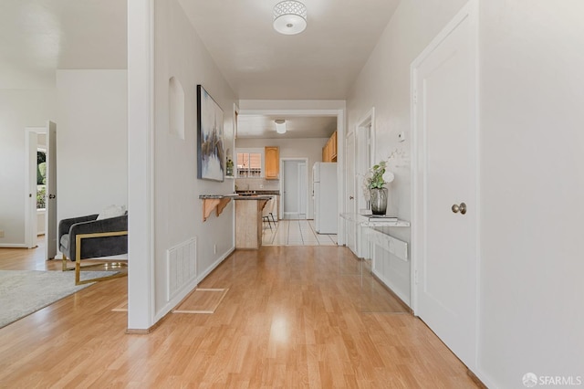 hall featuring light wood finished floors and visible vents