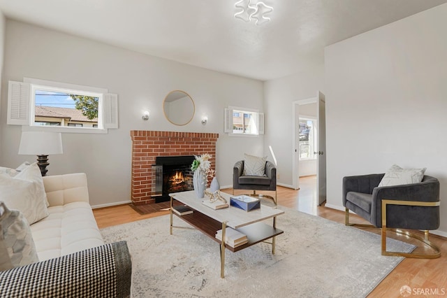 living area featuring a brick fireplace, a wealth of natural light, and wood finished floors