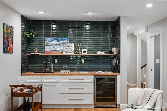 bar with beverage cooler, a sink, tasteful backsplash, recessed lighting, and indoor wet bar