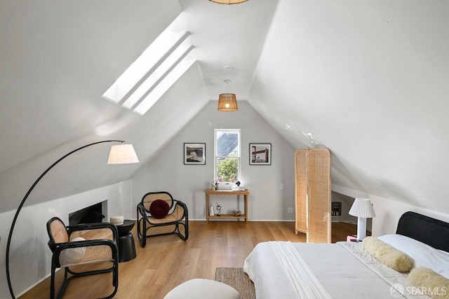 bedroom featuring vaulted ceiling with skylight and light wood-style flooring