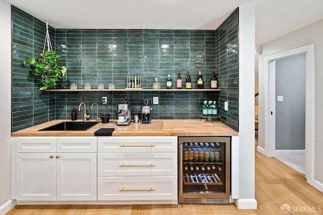 bar with wine cooler, decorative backsplash, wet bar, and a sink