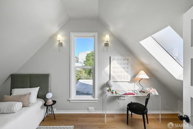 bedroom with lofted ceiling with skylight, visible vents, baseboards, and wood finished floors