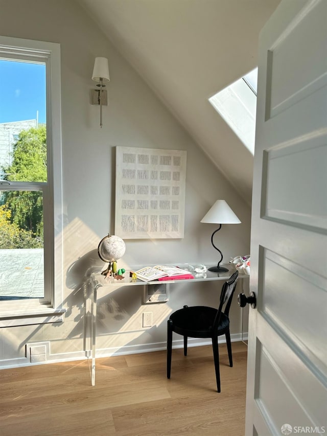 office featuring lofted ceiling with skylight, wood finished floors, and baseboards