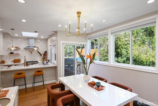 dining area with a skylight, recessed lighting, and light wood-type flooring