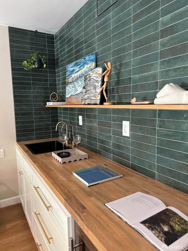 bar with tasteful backsplash, indoor wet bar, baseboards, and a sink