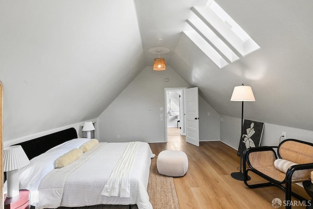 bedroom with vaulted ceiling with skylight and light wood finished floors