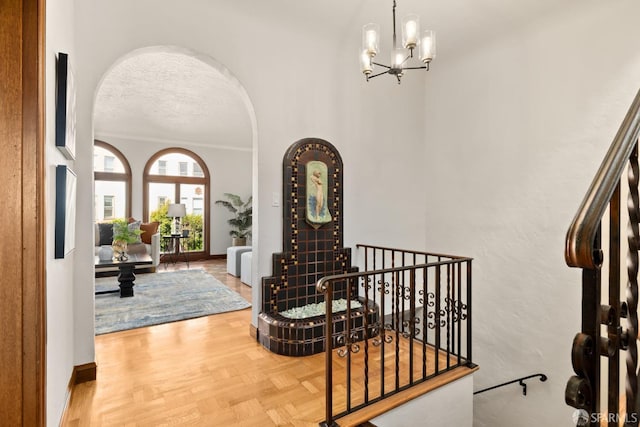 entrance foyer featuring an inviting chandelier, parquet floors, and a textured ceiling