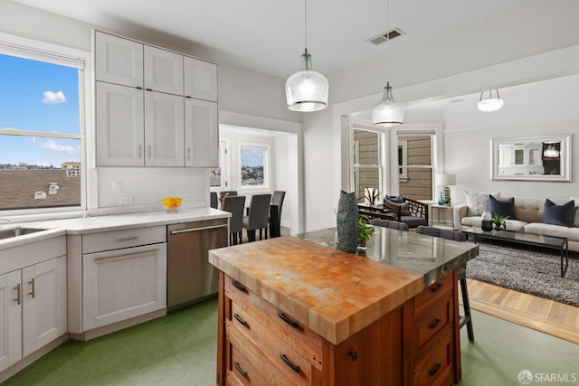 kitchen with a center island, white cabinetry, hanging light fixtures, and stainless steel dishwasher