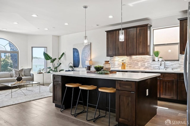 interior space with backsplash, light wood-style floors, pendant lighting, and a sink