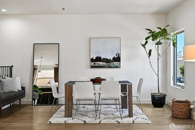 dining area with baseboards, a healthy amount of sunlight, wood finished floors, and visible vents