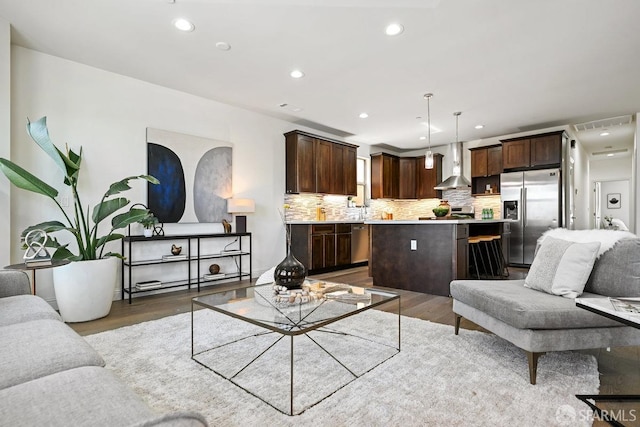 living room with recessed lighting, wood finished floors, and visible vents