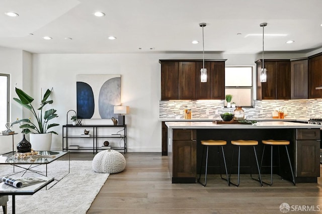bar featuring wood finished floors, pendant lighting, backsplash, baseboards, and recessed lighting