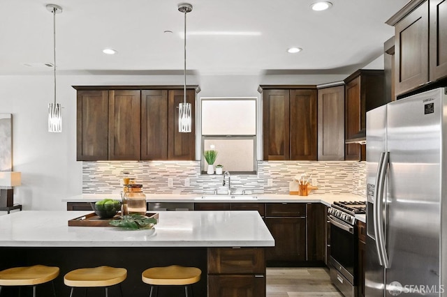 kitchen featuring dark brown cabinetry, stainless steel appliances, a breakfast bar, and a sink