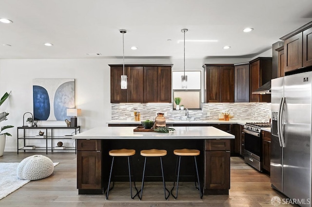 kitchen featuring backsplash, appliances with stainless steel finishes, a center island, and dark brown cabinetry