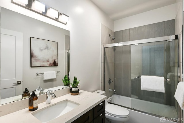 full bath with toilet, vanity, and bath / shower combo with glass door