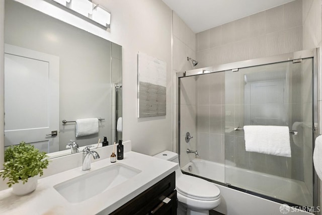 bathroom featuring toilet, vanity, and enclosed tub / shower combo