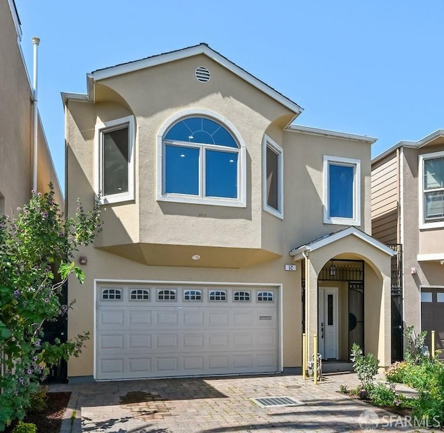view of front of property with stucco siding, an attached garage, and driveway