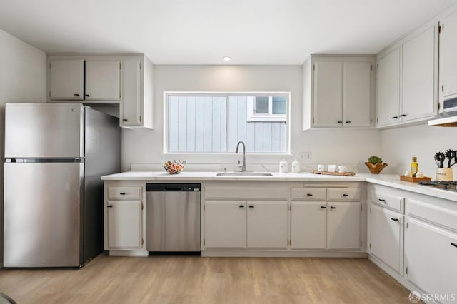 316 Gold Mine Dr, San Francisco, CA 94131 - kitchen with under cabinet range hood, light countertops, appliances with stainless steel finishes, light wood finished floors, and a sink