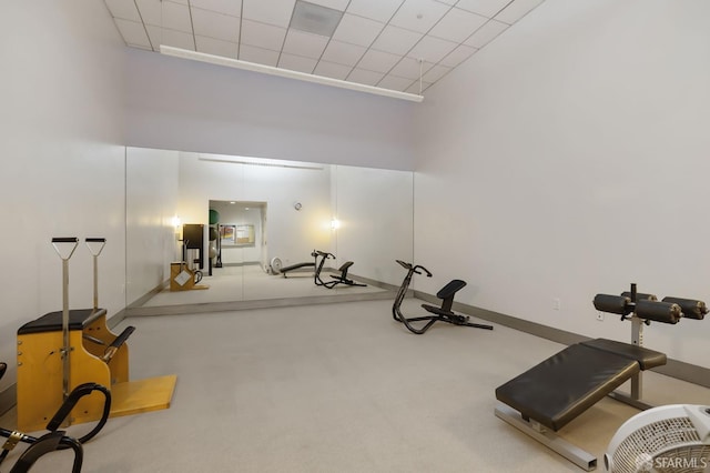 exercise room with carpet floors, a high ceiling, and a drop ceiling