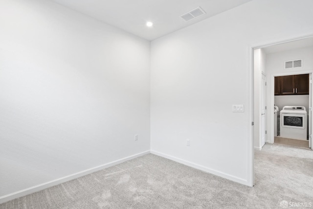 empty room featuring light carpet and washer and clothes dryer