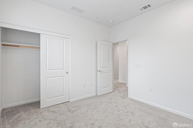 unfurnished bedroom featuring light carpet and a closet