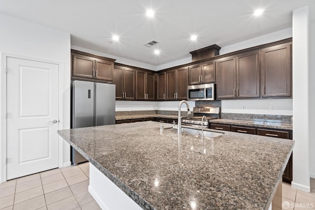 kitchen featuring dark brown cabinets, sink, stainless steel appliances, and an island with sink