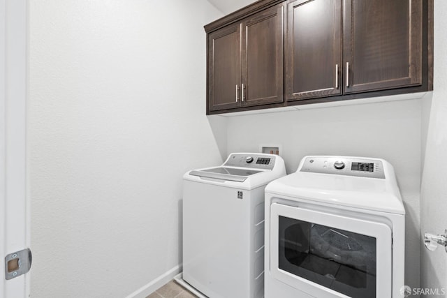 washroom featuring washer and clothes dryer, cabinets, and light tile patterned floors