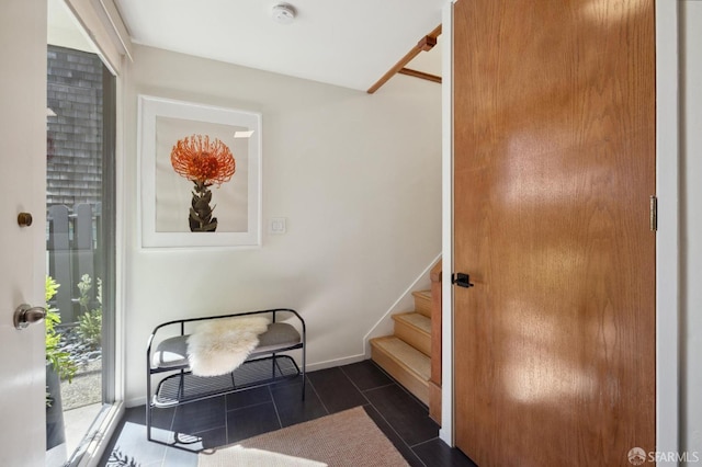 interior space featuring dark tile patterned flooring, stairway, and baseboards