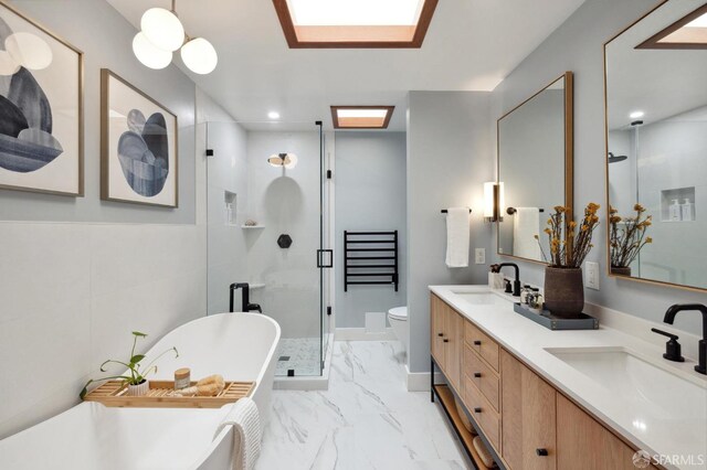 bathroom featuring marble finish floor, a sink, a shower stall, and a freestanding bath