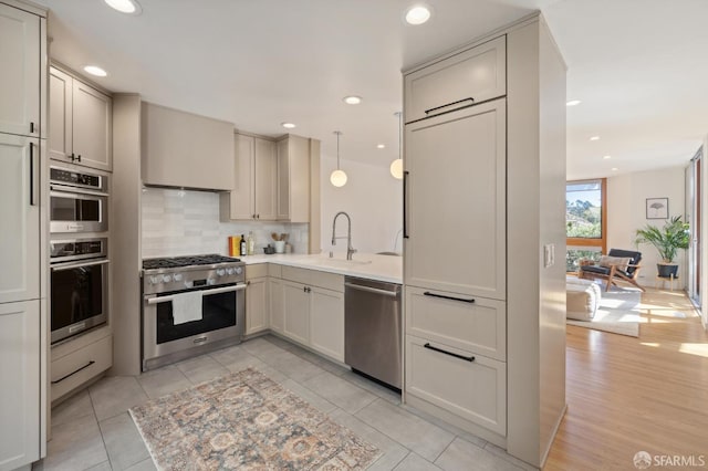 kitchen with recessed lighting, a sink, light countertops, appliances with stainless steel finishes, and tasteful backsplash